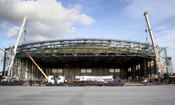 Two cranes lift the truss in place