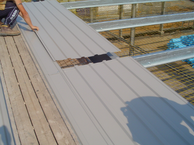 Liner sheet installation progressing into the span of the purlins with the installer working from a ‘Youngman’ board (Image courtesy of C A Roofing)