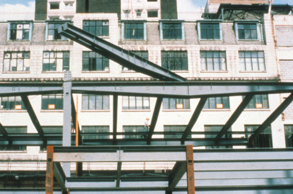 Tapered fabricated beams provide for service zones next to the columns